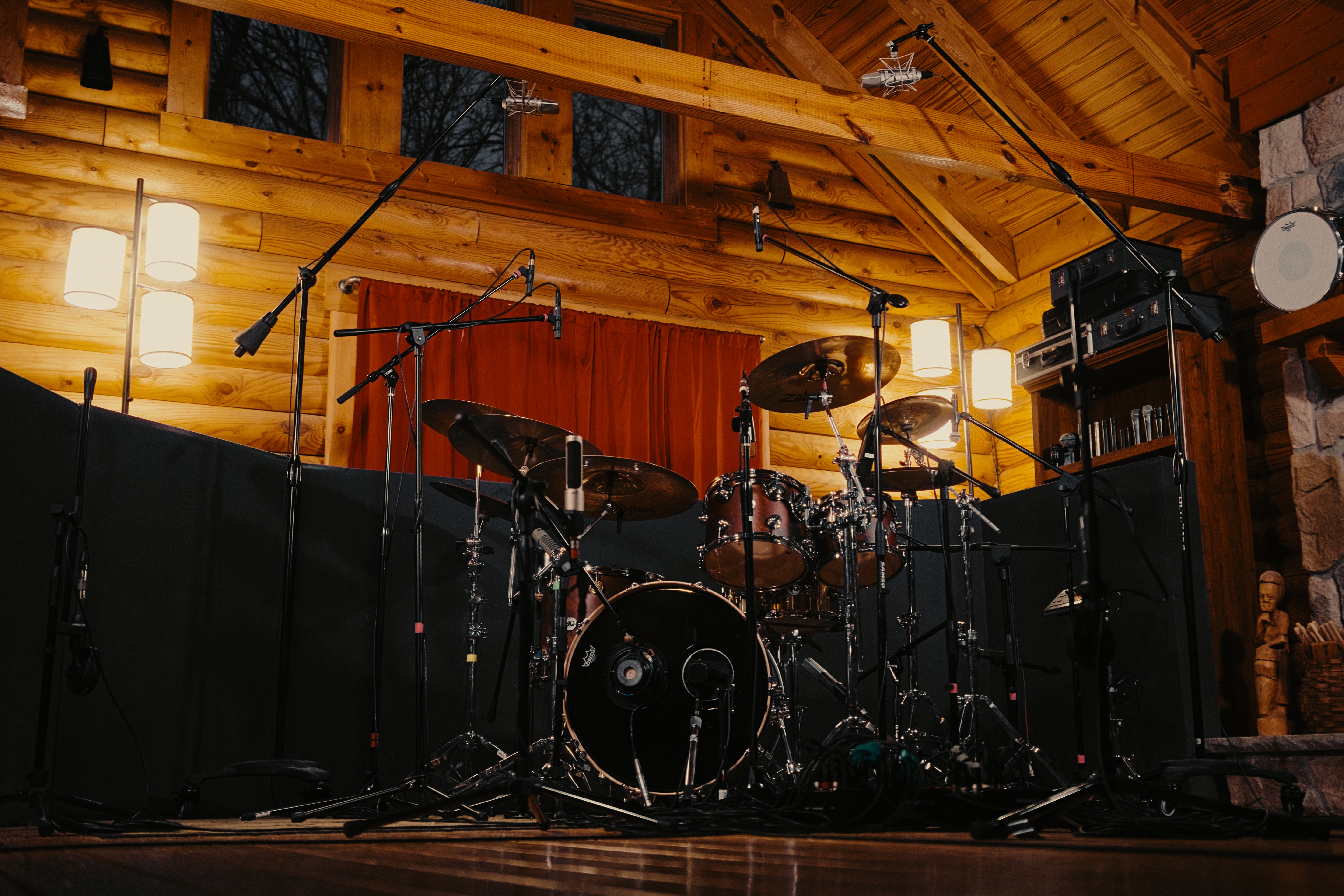 Powerkit drum setup in a wooden cabin under microphones and ambient lighting.